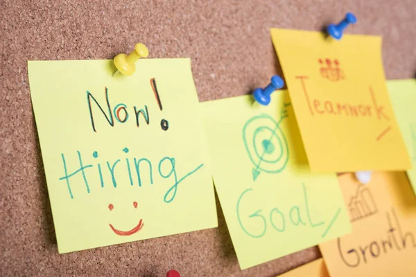 We re hiring text on sticky note or post is on cork bulletin