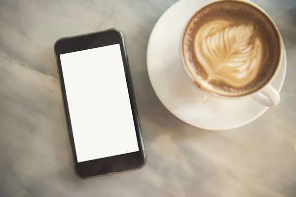 รูปแบบสมาร์ทโฟนที่มีโฟมลาเต้ฟอง, มุมมองด้านบนถ้วยกาแฟ — ภาพถ่ายสต็อก