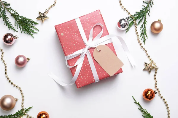 Vánoční dárková krabice s papírovým štítkem a vánoční ozdoby na bílém pozadí. zima, novoroční koncept. Byt ležel, horní pohled, kopírovací prostor. — Stock fotografie