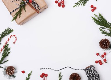 Noel kompozisyonu arka planında süslemeler ve beyaz arka planda hediye kutusu var. Kış, yeni yıl konsepti. Düz konum, üst görünüm, kopyalama alanı.