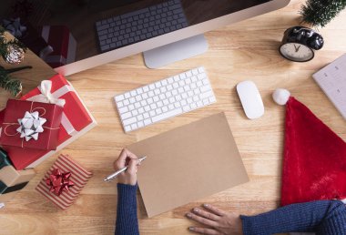 El yazısı Mutlu Noeller ve yeni yılınız kutlu olsun diye sahte tebrik kartı hazırlıyor. Masaüstünde Noel süsleri var..