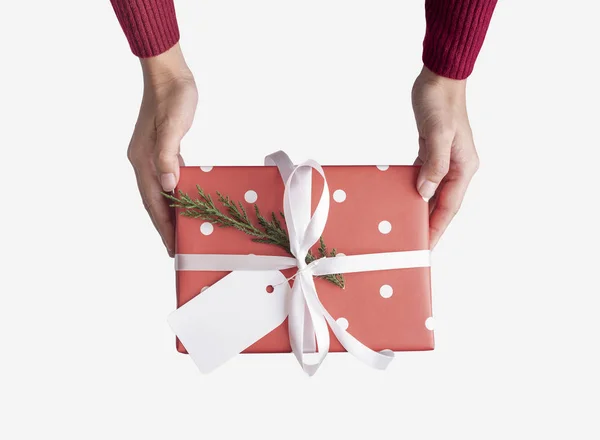 Nők kéz gazdaság piros ajándék doboz és papír címke elszigetelt fehér háttér karácsony és újév koncepció. — Stock Fotó