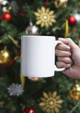Kadınlar Noel ağacı arka planında beyaz seramik kahve fincanı tutuyorlar. Yaratıcı reklam metni ya da tanıtım içeriği için maket.