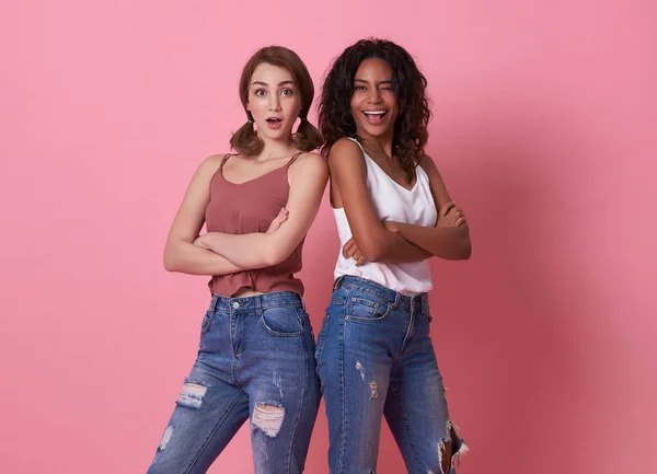 Mutlu gülümseyen güzel kız arkadaş kameraya bakıyor pembe arka planda izole edilmiş rahat gömlekler giyiyor..