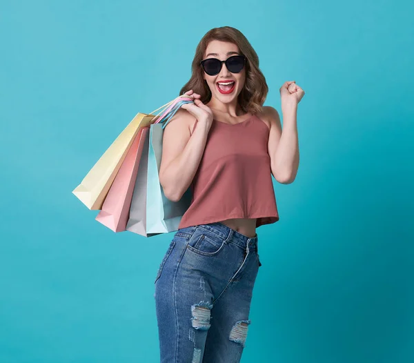 Glad vacker ung kvinna hand hålla shoppingväska isolerad över blå bakgrund. — Stockfoto