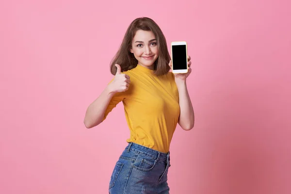 Портрет щасливої молодої жінки, що показує на порожньому екрані мобільний телефон ізольований на рожевому фоні . — стокове фото