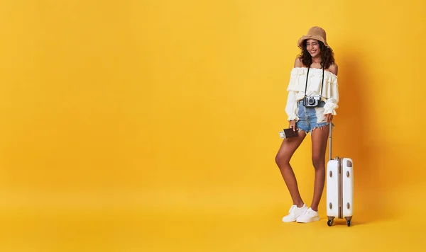 Feliz mujer africana sonriente vestida con ropa de verano con equipaje disfrutando de su escapada de vacaciones de verano en fondo de bandera amarilla con espacio para copiar . — Foto de Stock