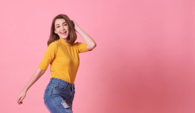 Heyecanlı güzel kadın mutluluğu pembe arka planda izole edilmiş günlük sarı tişört giyiyor..