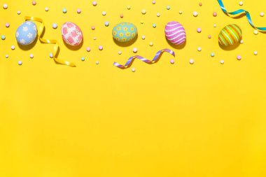 Yaratıcı Paskalya bayramı düzenleme yumurtaları sarı arka planda kurdele köpüğü partisiyle boyanmış el yapımı. Mevsimlik düz yatak konsepti..