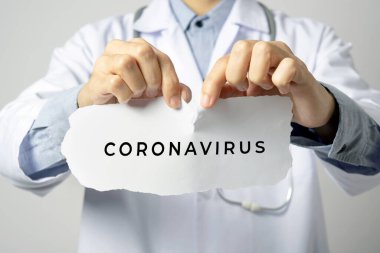 Doktor, Coronavirus 'un gri duvar arkaplanlı yazısını tutuyor. Corona virüsüne karşı konsept önlem.