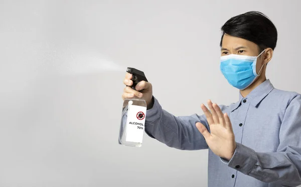 Asia man using spray alcohol cleaning for protect anti virus bacteria.  Preventive measures against corona virus.