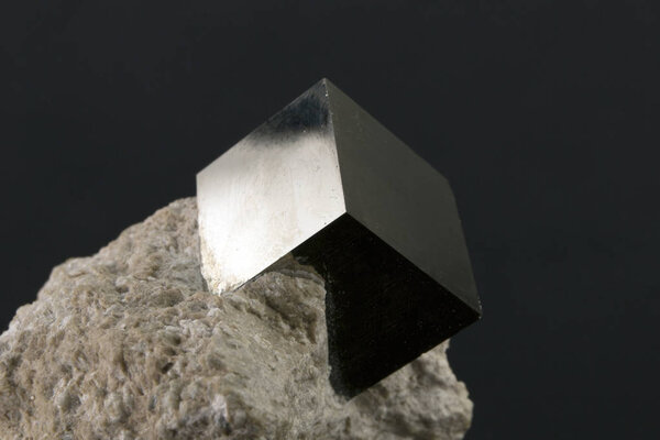 Shiny smooth regular shape pyrite cube on a dark background