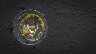 Siyah betonun üzerinde yeşil zeytinli martini.