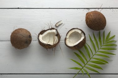 Beyaz ahşap bir masada yeşil yapraklı hindistan cevizi.