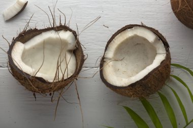 Beyaz ahşap bir masada yeşil yapraklı hindistan cevizi.