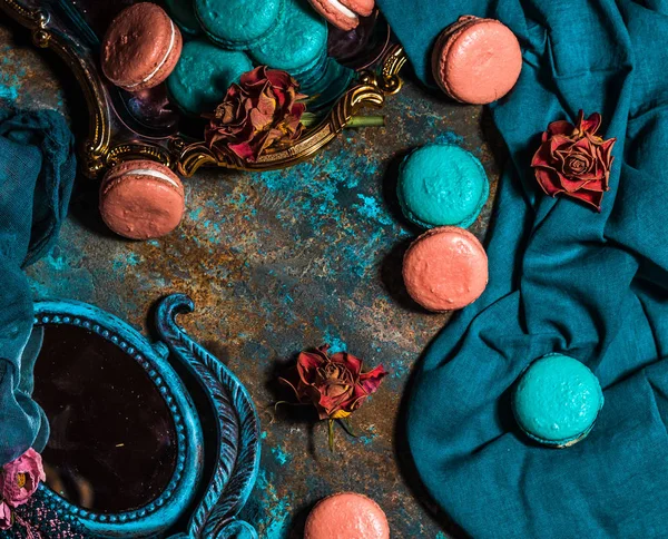 Macarons ve rustik yüzey üzerinde kurutulmuş güller