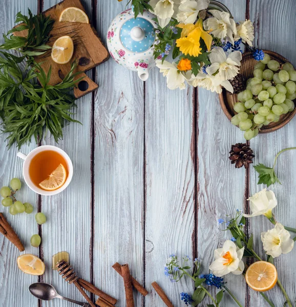 Šálek čaje s citronem, květin a vinné hrozny — Stock fotografie