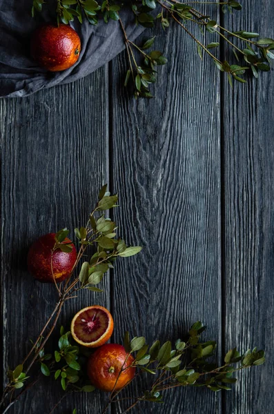 Blood oranges with leaves on wooden table