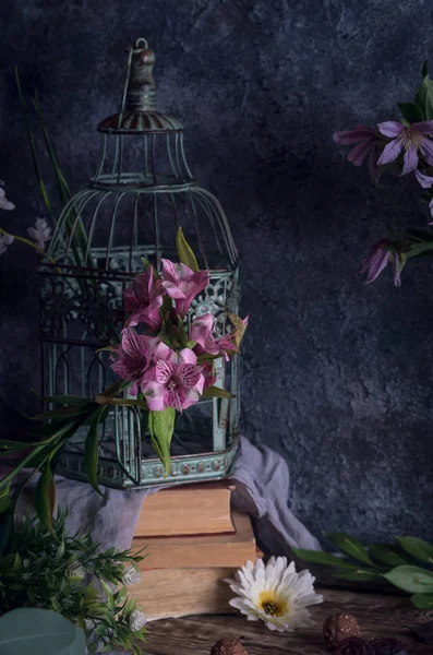 Vintage cage on books and flowersib vase