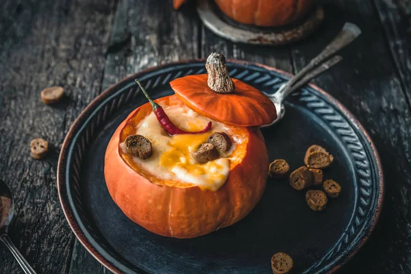 biberli kabak çorbası ve ahşap masadaki kabakların içinde peynir kabuğu.