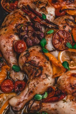 Kızarmış tavuk budu, sebzeli ve portakallı, metal tepside.