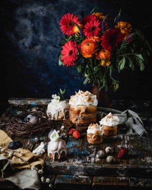 Ev yapımı Paskalya turtalarının yakın çekimi. Yuvalarında yumurtaları kırsal ahşap arka planda. Taze bahar çiçekleri, yeşil yapraklar ve söğütler. 