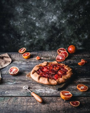 Tahta tahtada kan turtası ve ahşap arka planda portakal dilimleri var.