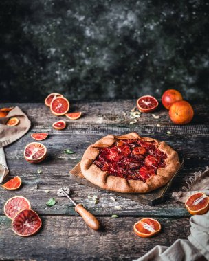 Tahta tahtada kan turtası ve ahşap arka planda portakal dilimleri var.