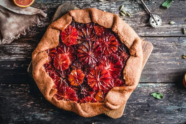 Tahta tahtada kan turtası ve tahta arka planda portakal dilimleri var.