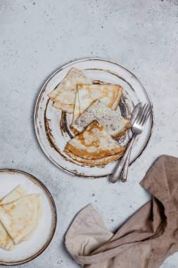 Çatal ve bıçaklı fırında krep ve eski püskü gri arka planda tekstil.