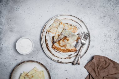 Çatal ve bıçaklı fırında krep ve eski püskü gri arka planda tekstil.