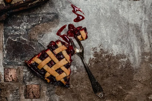 cherry pie slice with fork over brown concrete background, top view. traditional seasonal dessert