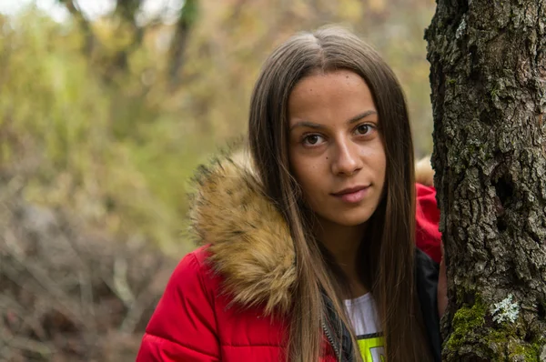Ung kvinna ensam på en skog som bär röd överrock — Stockfoto
