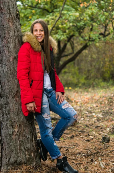 Mujer joven sola en un bosque con abrigo rojo —  Fotos de Stock