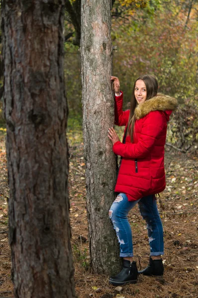 Młoda kobieta sama w lesie na sobie czerwony płaszcz — Zdjęcie stockowe