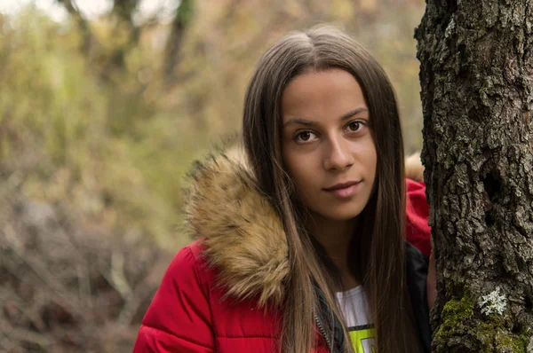 Mujer joven sola en un bosque con abrigo rojo —  Fotos de Stock