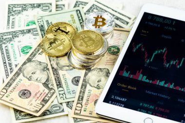 Kağıt dolar banknotları üzerine yığılmış Bitcoin yığınları beyaz modern tablet, borsa şamdan şeması, sanal para birimi, dijital kripto, metal kripto paralar.