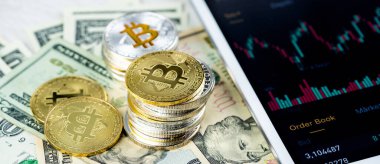 Kağıt dolar banknotları üzerine yığılmış Bitcoin yığınları beyaz modern tablet, borsa şamdan şeması, sanal para birimi, dijital kripto, metal kripto paralar.