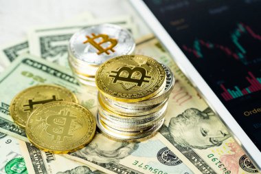 Kağıt dolar banknotları üzerine yığılmış Bitcoin yığınları beyaz modern tablet, borsa şamdan şeması, sanal para birimi, dijital kripto, metal kripto paralar.