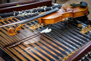 Antique violin and violin bow lying on dulcimer. Close up a violin instrument and cymbal before a concert. Music concept background clipart