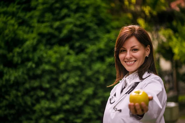 Sonriente médico que le ofrece manzana —  Fotos de Stock