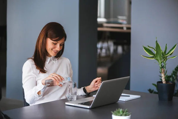 Affärskvinna dricksvatten i office. — Stockfoto