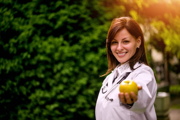 Medico donna che offre mela — Foto Stock