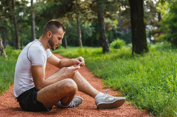 Hombre comprobación de teléfono móvil en el parque — Foto de Stock