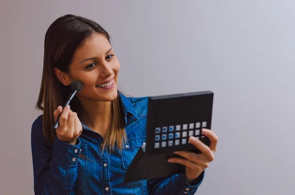 Jovem mulher aplicando maquiagem — Fotografia de Stock