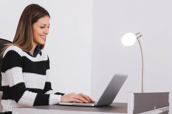 Mujer sonriente joven usando el ordenador portátil — Foto de Stock