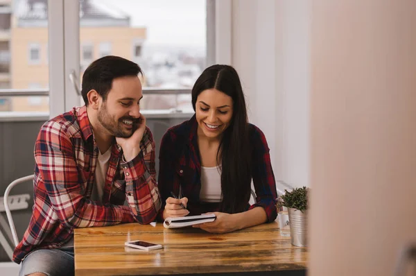 Pregnant couple writing on a notepad — Stock Photo, Image