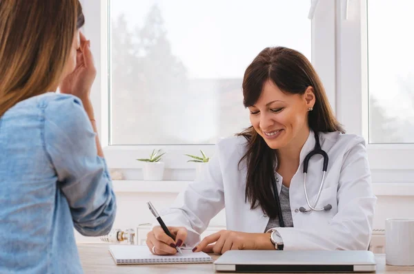 Doctor writing and smiling with patient — Stock Photo, Image