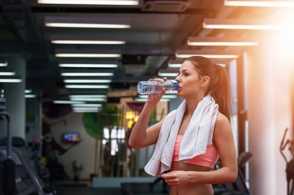 Девушка пьет воду в спортзале — стоковое фото