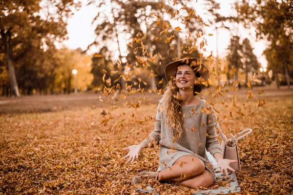 Mujer lanzando las hojas amarillas — Foto de Stock